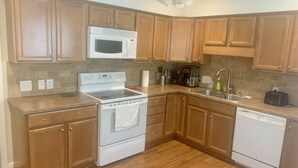 A kitchen with wooden cabinets, a white stove, a microwave, a dishwasher, and a sink. - Spacious  Home with Incredible Location (Charlotte)