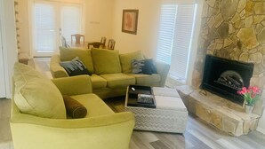A living room with a stone fireplace, a sofa, and a coffee table. - Spacious  Home with Incredible Location (Charlotte)