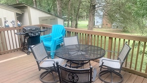 A deck with a round table and four chairs, a grill, and blue chairs. - Spacious  Home with Incredible Location (Charlotte)
