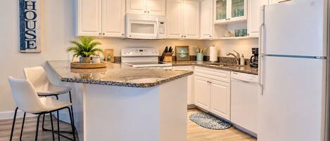 A modern kitchen with white cabinetry, a granite countertop, and a central island.
