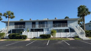 Ein Hotel mit zwei Etagen, einem Balkon, einem Parkplatz und Palmen.