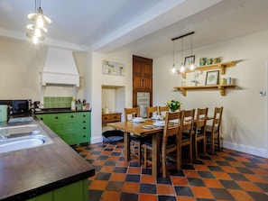 A kitchen with a dining area, featuring a checkered floor, green cabinets, and a wooden dining table with chairs.