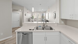 Een moderne keuken met witte kastjes, een dubbele spoelbak en een vaatwasser.