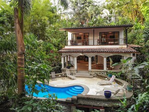 A two-story house with a swimming pool, surrounded by lush greenery. - Villa Monos Bailarines: 2BR Home + 1BR Studio Guest House, Pool & Wildlife! (Manuel Antonio)