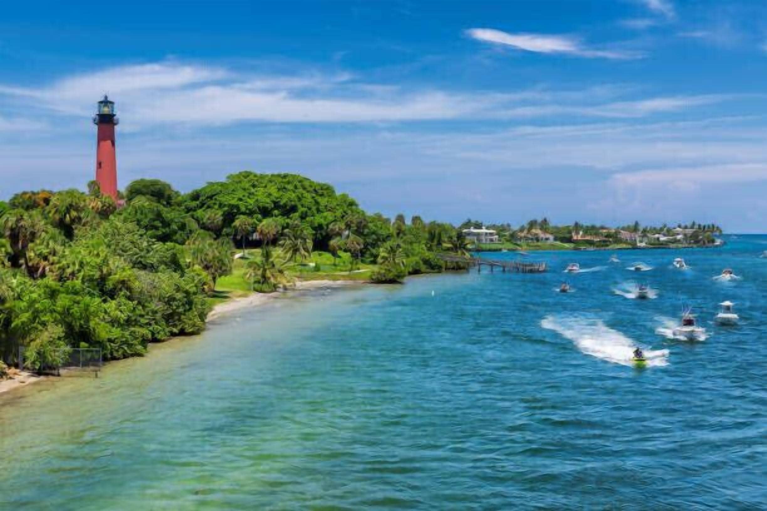 A coastal scene with a lighthouse, lush greenery, and a clear blue sky.