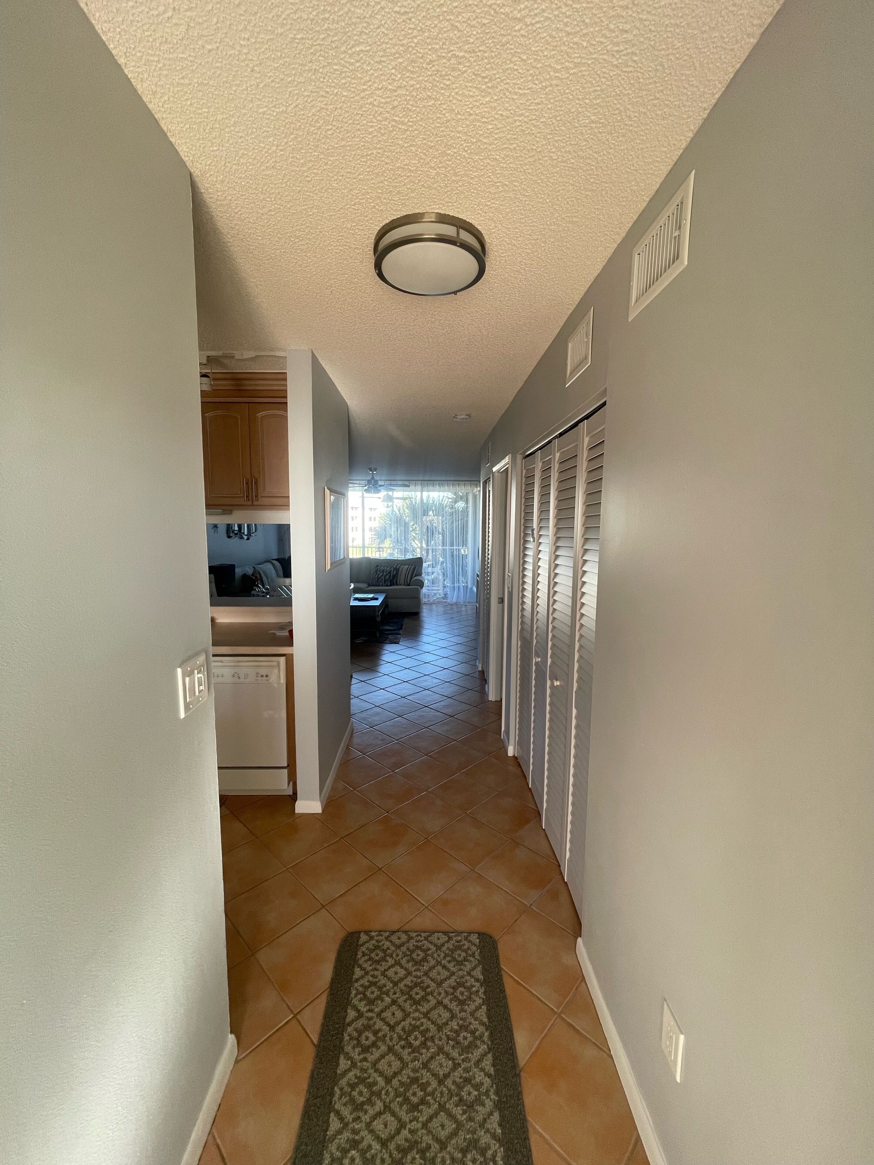 A hallway with a kitchen area, a dining area, and a view of the outdoors.