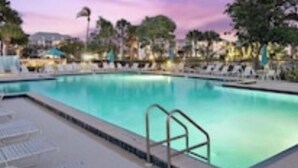 Piscina com espreguiçadeiras e um mastro.