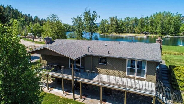 Une maison à deux étages avec un balcon, des fondations en pierre et une vue sur un lac.