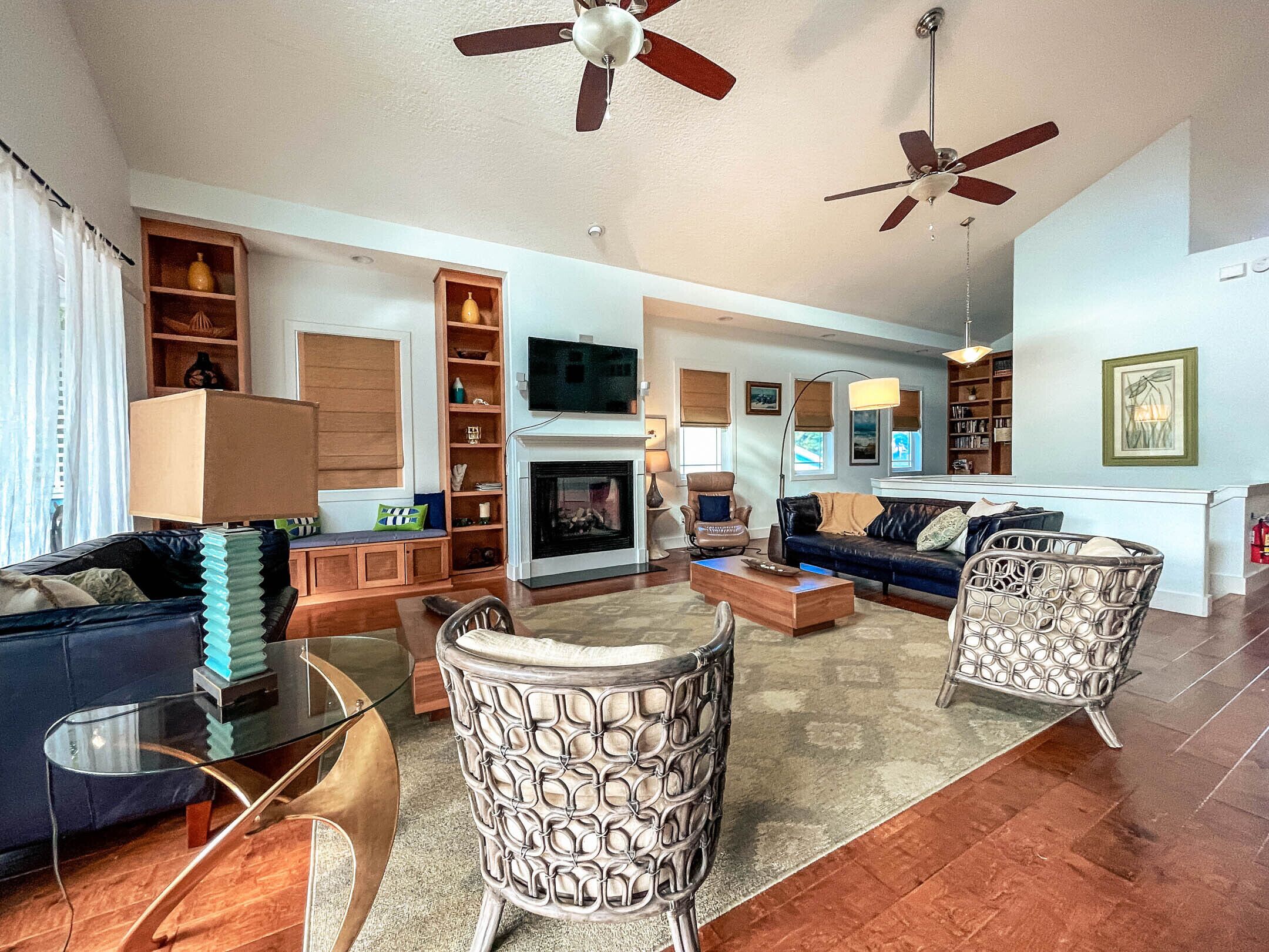 A spacious living room with a fireplace, comfortable seating, and ceiling fans.