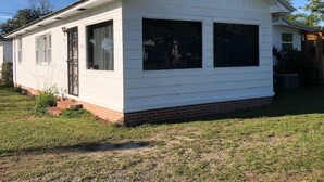 A single-story white house with a brick foundation, large windows, and a small porch. - Entire House, close to downtown, airport, masters and Fort Eisenhower. (Augusta)