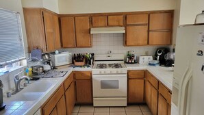 Une cuisine de taille réduite, avec des meubles en bois, une cuisinière blanche, un four à micro-ondes et un réfrigérateur.