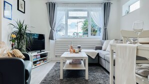 Una sala de estar moderna con un sofá, una mesa de centro, un televisor y un comedor con una mesa y sillas.
