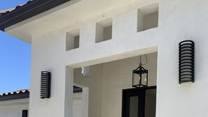 Un edificio moderno con fachada blanca, una puerta negra y un pequeño porche.