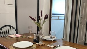 Ein Esstisch ist gedeckt mit Tellern, Gläsern und einer Vase mit Blumen.