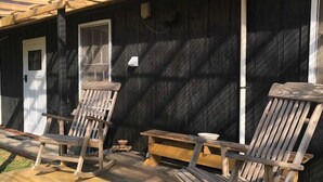 Eine hölzerne Veranda mit zwei Adirondack-Stühlen und einer Bank.