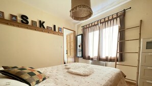 Un dormitorio con cama, una escalera, un armario y una estantería en la pared con fotos y cartas enmarcadas.