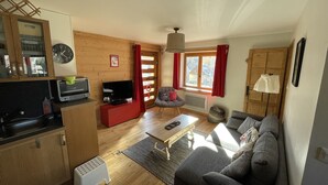 Una sala de estar acogedora con un sofá, televisión y armarios de madera.
