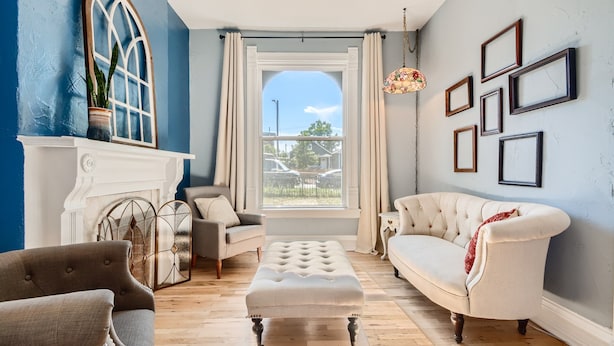 Un salon avec une cheminée, une grande fenêtre et un canapé blanc.