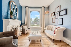 A living room with a fireplace, a large window, and a white sofa. - Vintage Charm in the Heart of Denver (Denver)