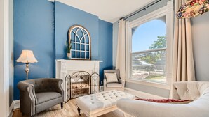Une pièce avec un mur bleu, une cheminée blanche et une vue sur l’extérieur.