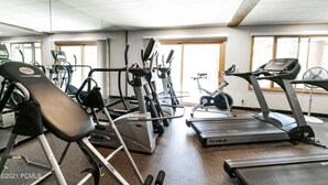 Une salle de sport équipée de tapis de course, de vélos elliptiques et d’un banc de musculation.