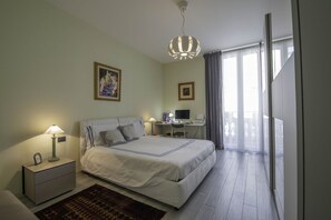 Une chambre à coucher avec un lit, des tables de chevet, un bureau et un ordinateur.