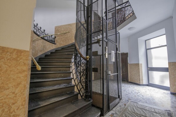 Un escalier en colimaçon avec des rampes en métal, un sol carrelé et une grande fenêtre laissant entrer la lumière naturelle.