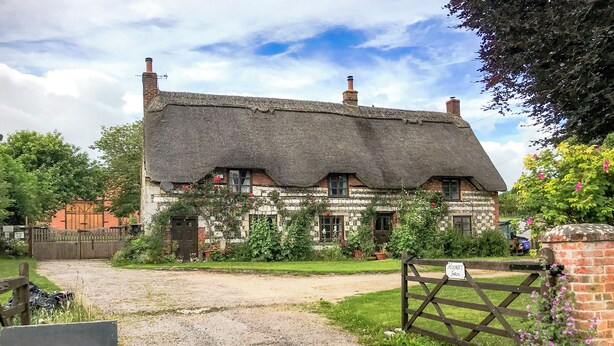 A traditional thatched-roof house with a gravel driveway and a wooden gate. - Hoopers Farmhouse - UK36307 (Tilshead)