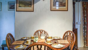 A dining area with a wooden table set for four, surrounded by chairs. There are framed pictures on the wall above the table. - Hoopers Farmhouse - UK36307 (Tilshead)