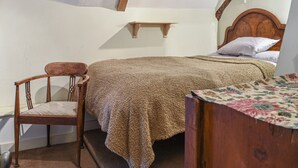 A bedroom with a wooden bed, a chair, and a small shelf. - Hoopers Farmhouse - UK36307 (Tilshead)