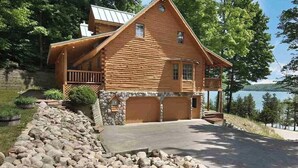Eine Blockhütte mit Steinunterbau, einer Veranda und einer Garage.