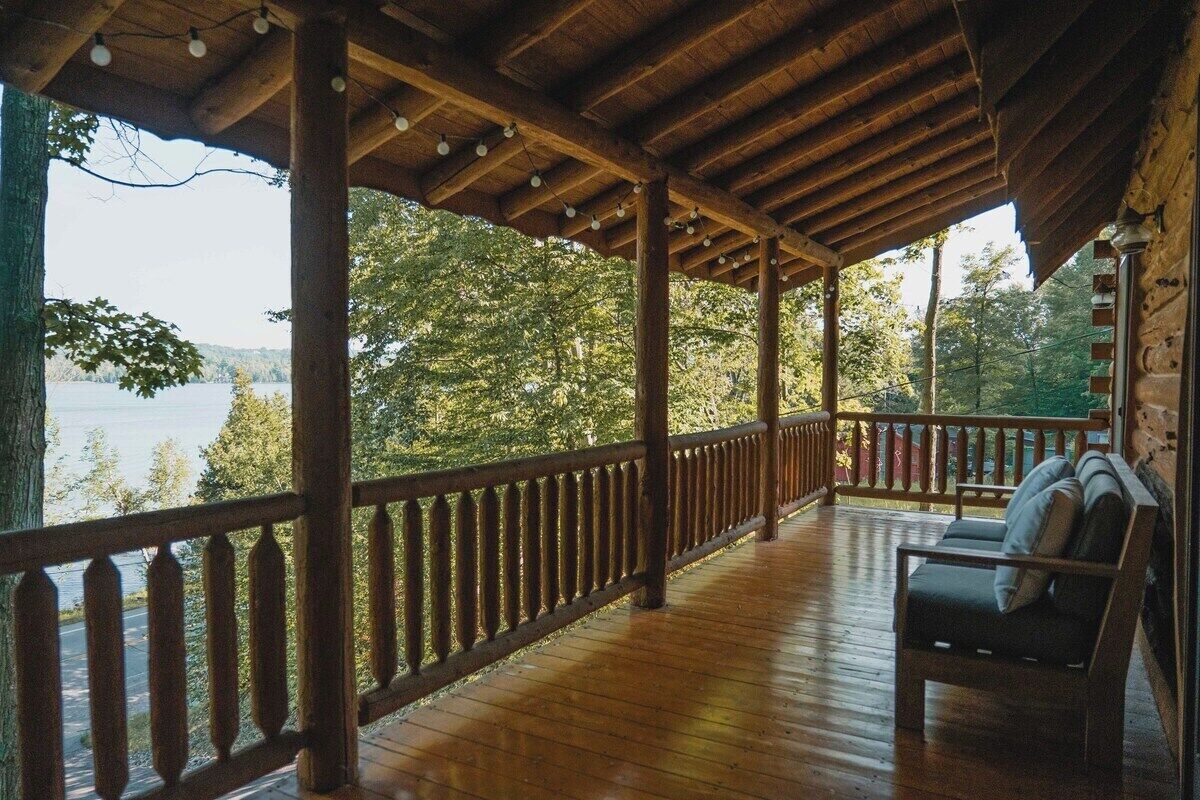 A wooden deck with a railing, a bench, and a view of a lake.