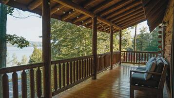 A wooden deck with a railing, a bench, and a view of a lake.