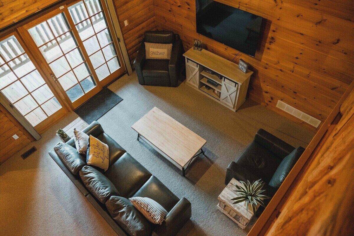 Un acogedor interior de cabaña con un sofá, una mesa de centro, un televisor y una chimenea.