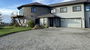 A modern two-story house with a stone facade, a balcony, and a garage.