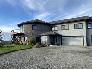 Uma casa moderna de dois andares com fachada de pedra, uma varanda e uma garagem.