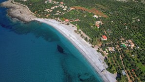 Vista aérea de una zona costera con playa, aguas azules cristalinas y vegetación circundante.