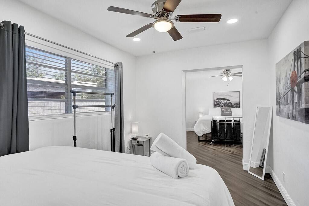 Una habitación de hotel moderna con una cama grande, ventilador de techo y vista por la ventana.