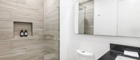 A modern bathroom with a shower, toilet, and sink.