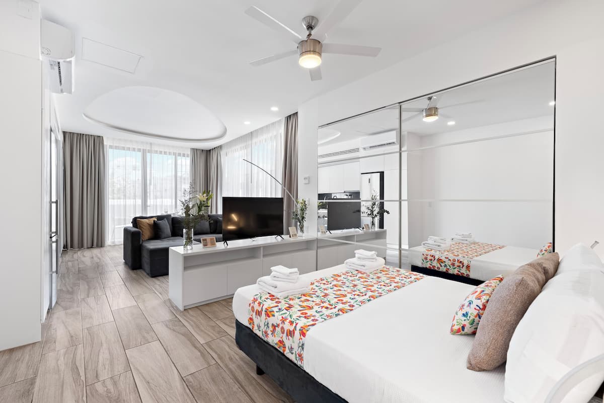 Une chambre d’hôtel moderne équipée d’un grand lit, d’un canapé, d’un bureau, d’une télévision et d’un miroir.