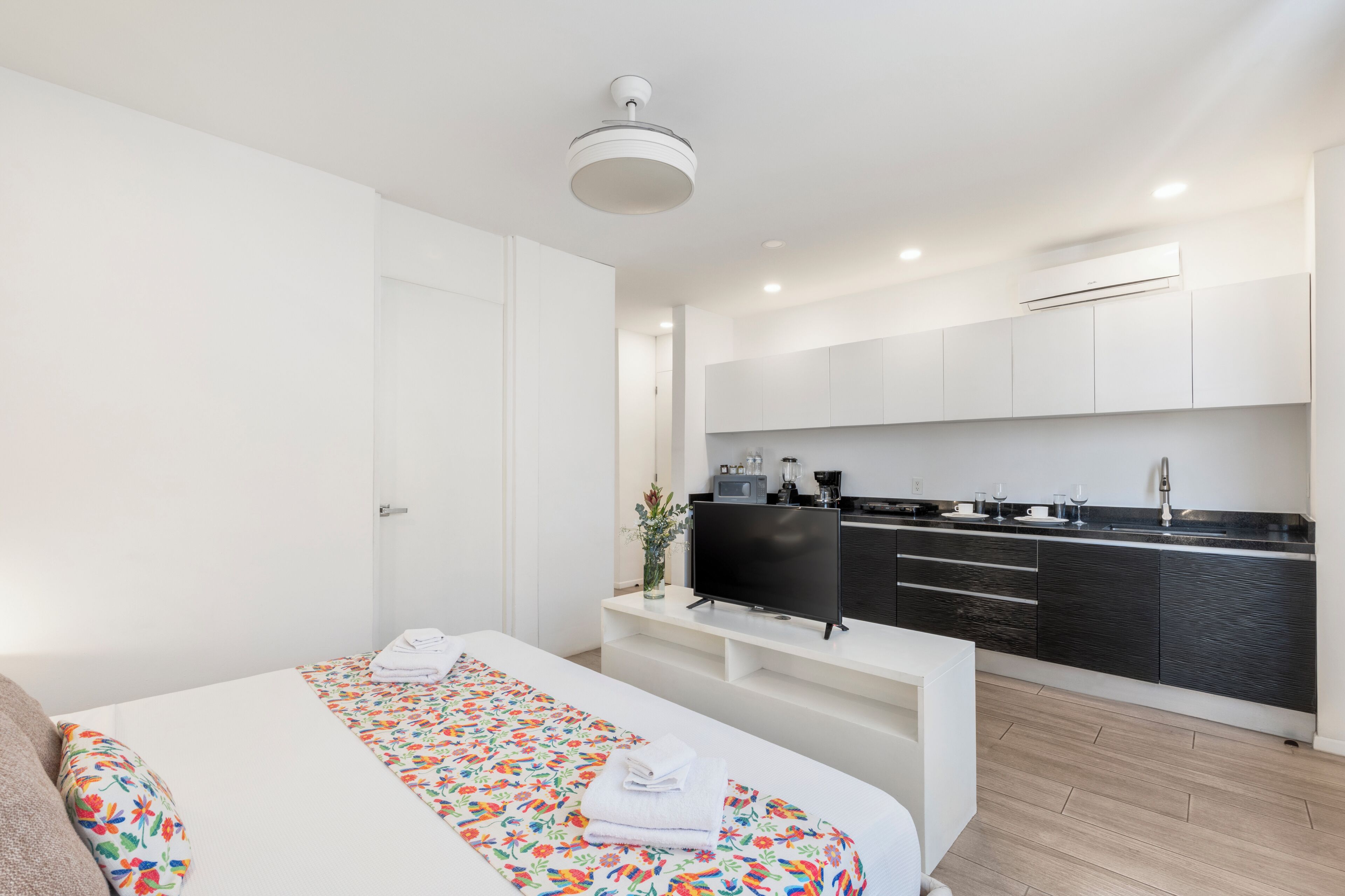 Une chambre d’hôtel moderne équipée d’un lit, d’une télévision, d’une kitchenette et d’une salle de bain.