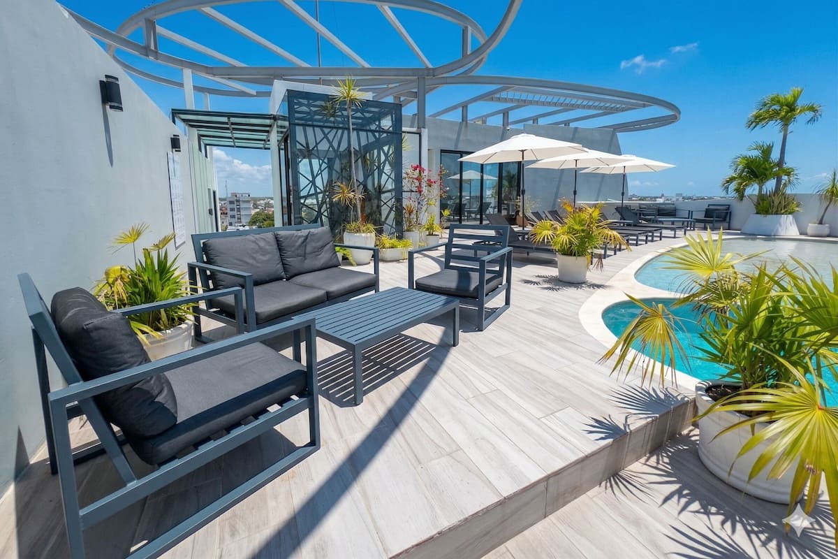 Une terrasse sur le toit avec des sièges en plein air, une piscine et des plantes en pot.