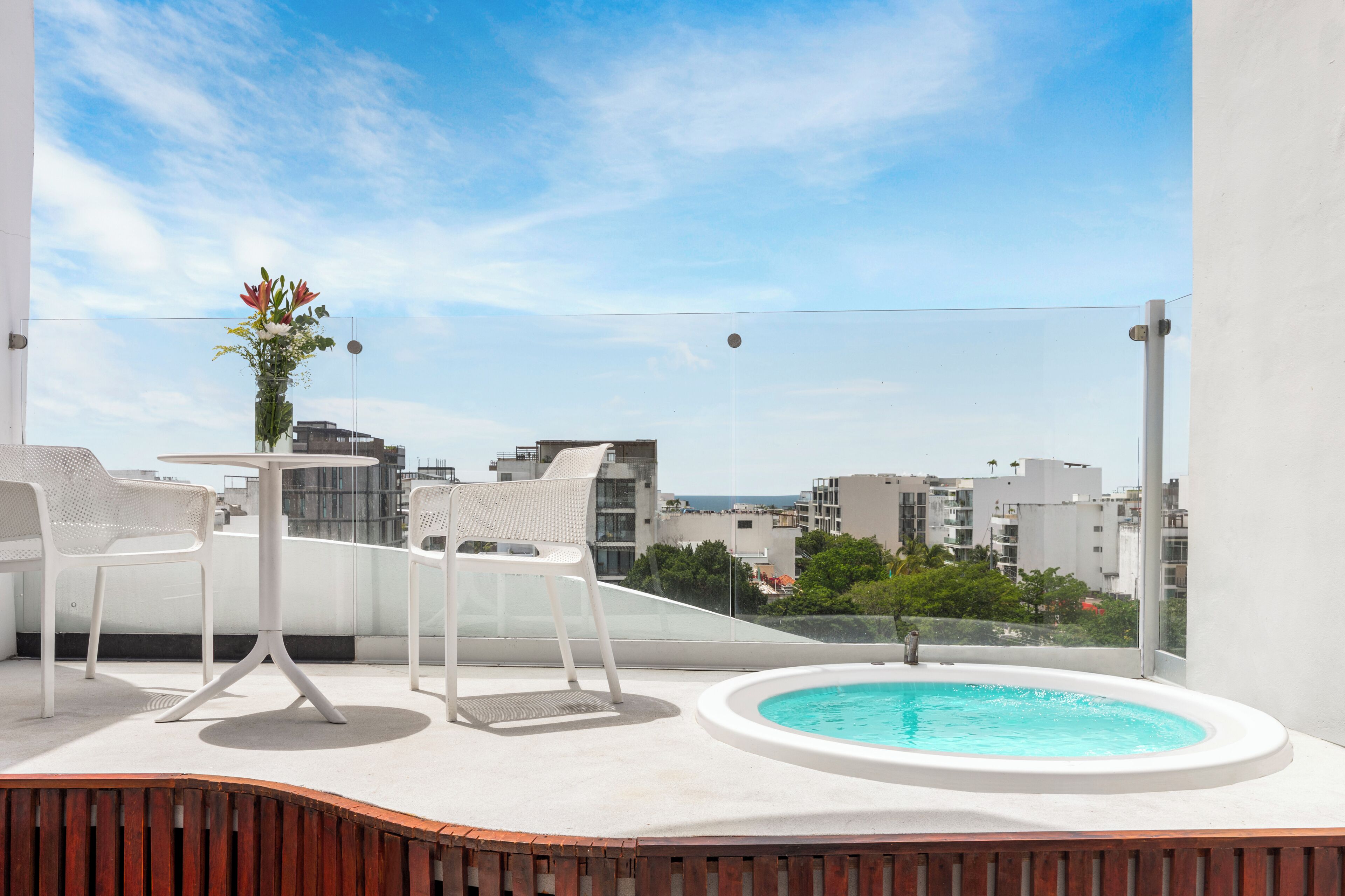 Eine Dachterrasse mit Pool, weißen Stühlen, einem Tisch und Blumenarrangements.