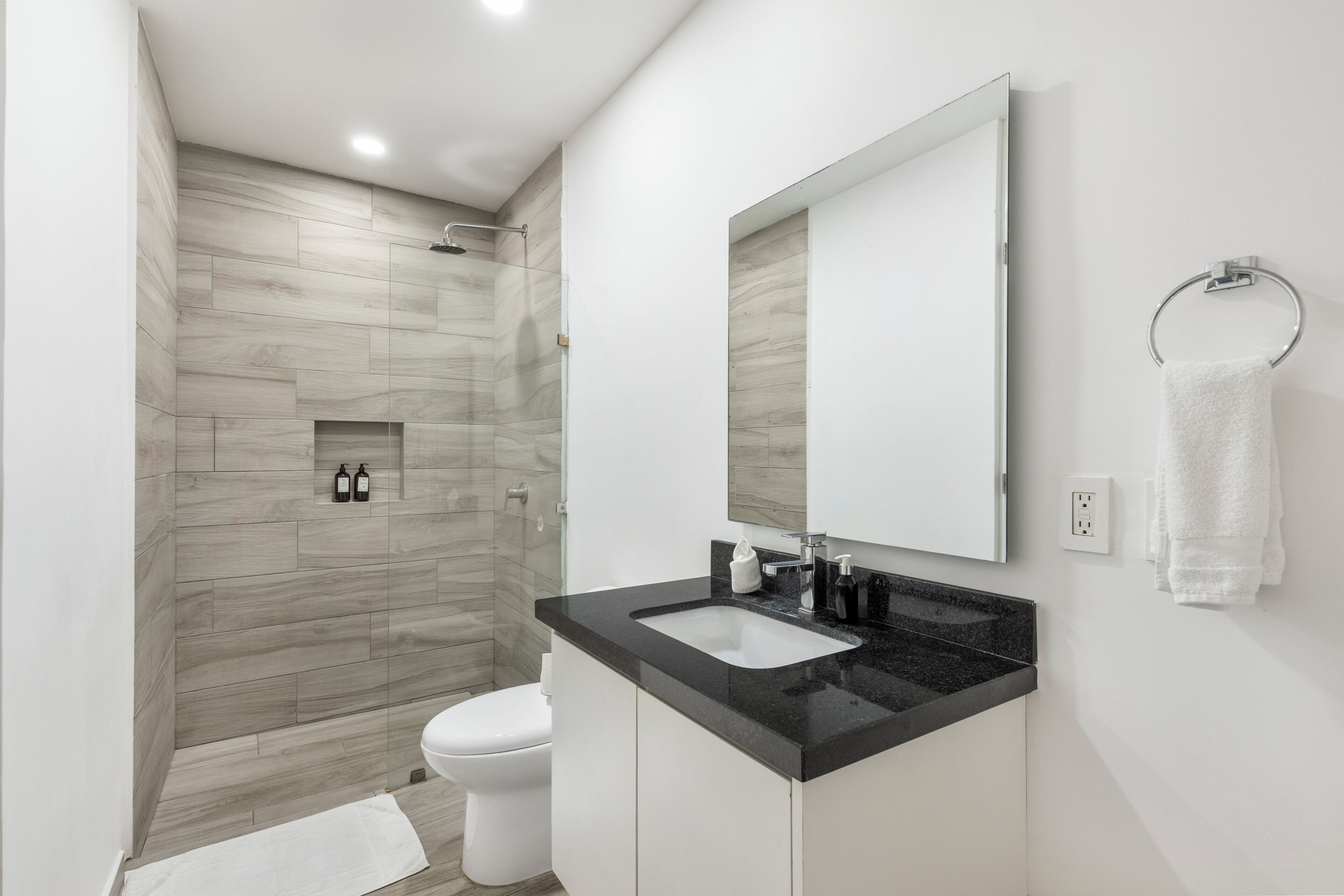 A modern bathroom with a shower, toilet, and sink.