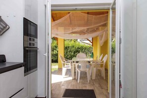Enjoy meals in the kitchen with stainless steel appliances and adjacent dining area under a canopy.