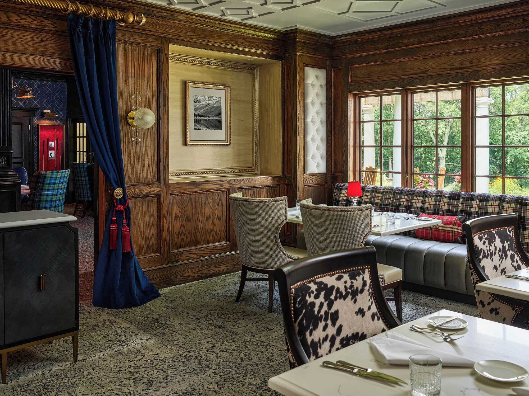 A dining area with wooden paneling, a red telephone, and a bench with plaid upholstery.