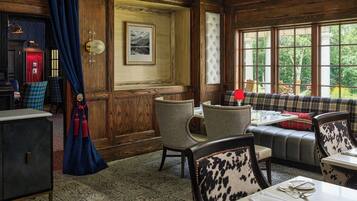 A dining area with wooden paneling, a red telephone, and a bench with plaid upholstery.