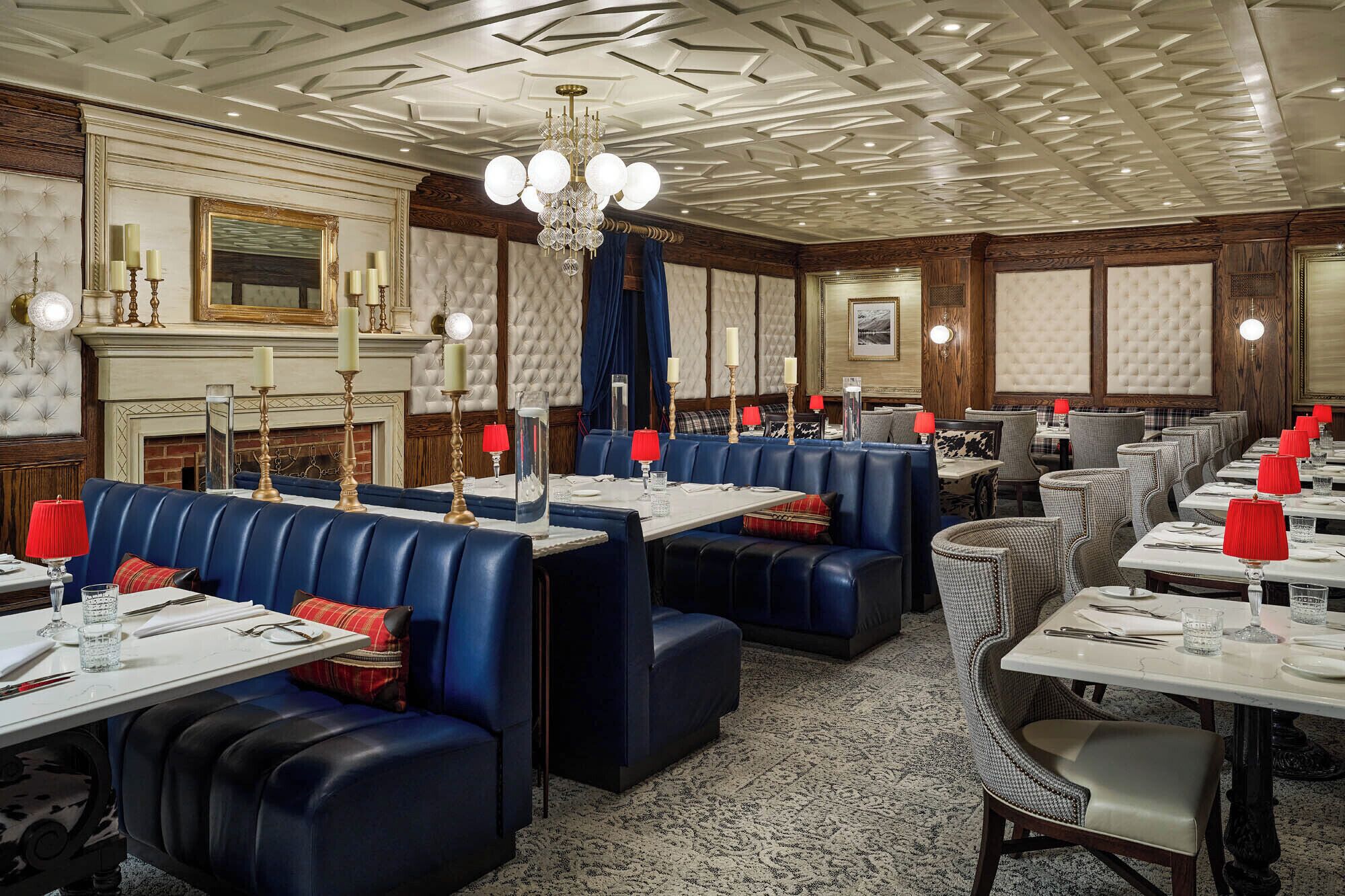 A formal dining room with leather booths and tables, a chandelier, and a fireplace.