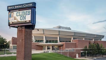 A sports facility with a large digital sign reading "CLIMB ON" and "Bryce Jordan Center" at dusk.