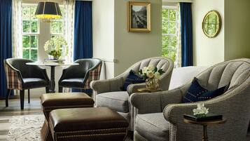 A room with two armchairs, a sofa, a table with a vase of flowers, and a picture on the wall.